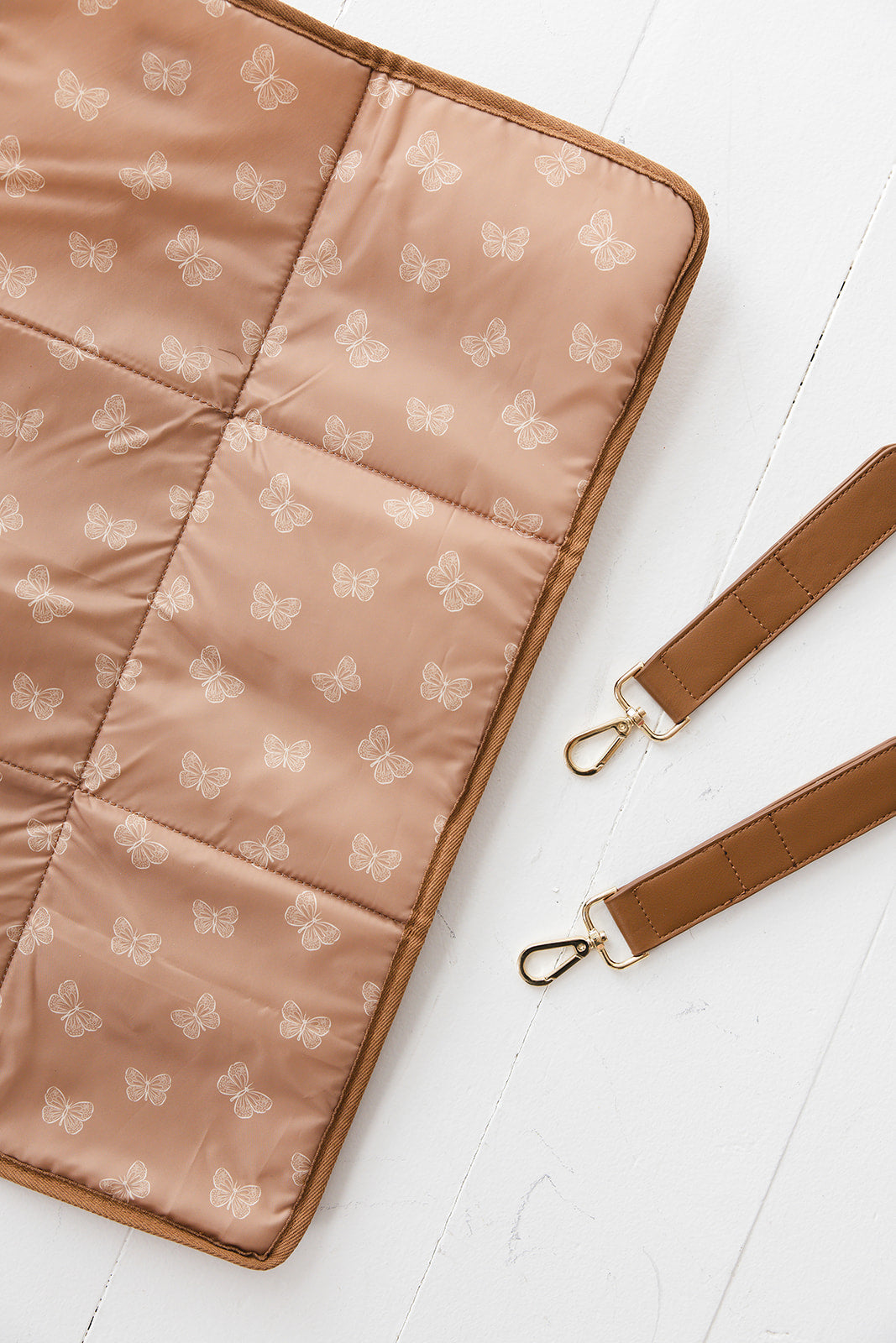 Brown faux leather large diaper bag with checkered cross body strap, insulated bottle pockets, changing mat, and stroller straps.
