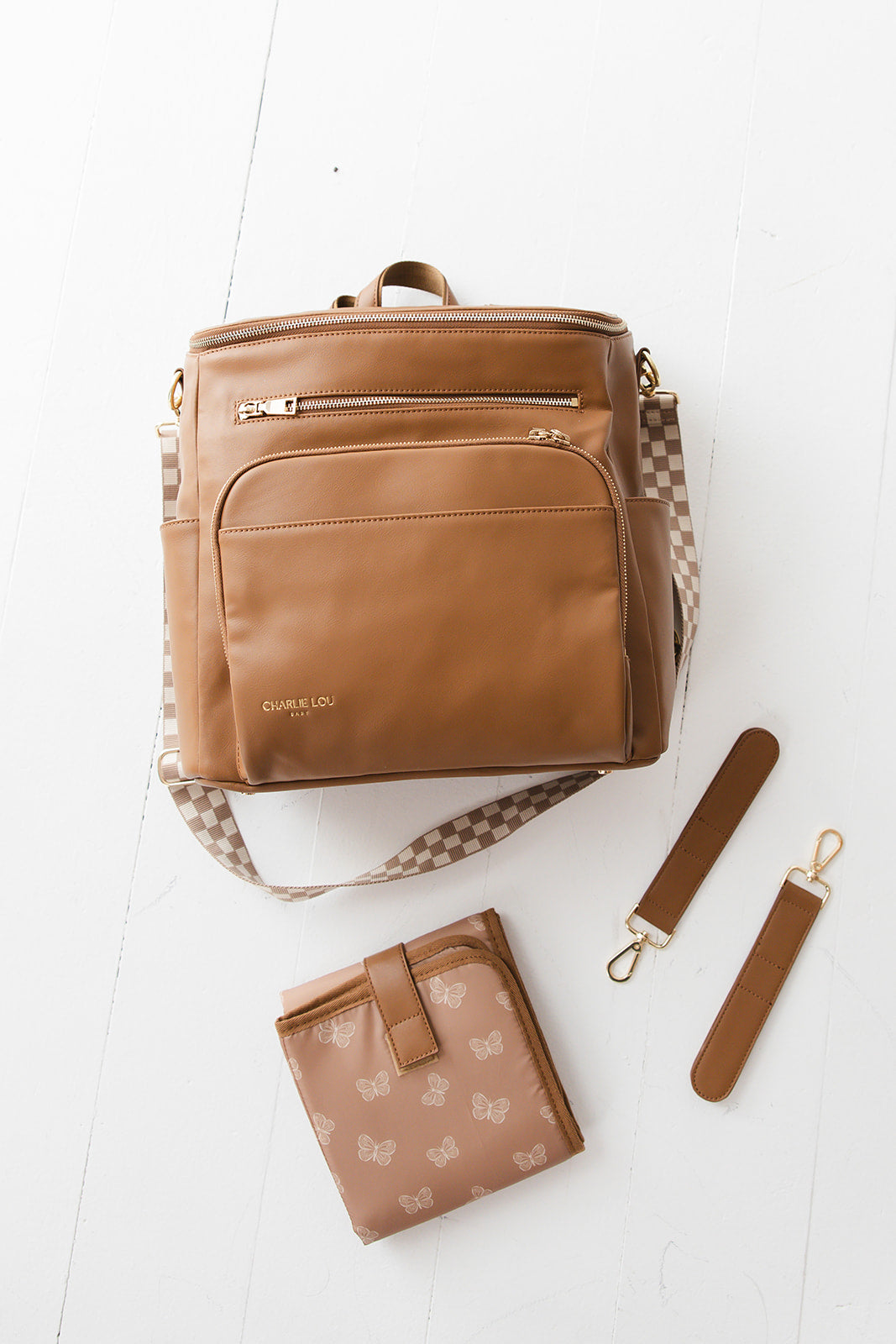 Brown faux leather large diaper bag with checkered cross body strap, insulated bottle pockets, changing mat, and stroller straps.