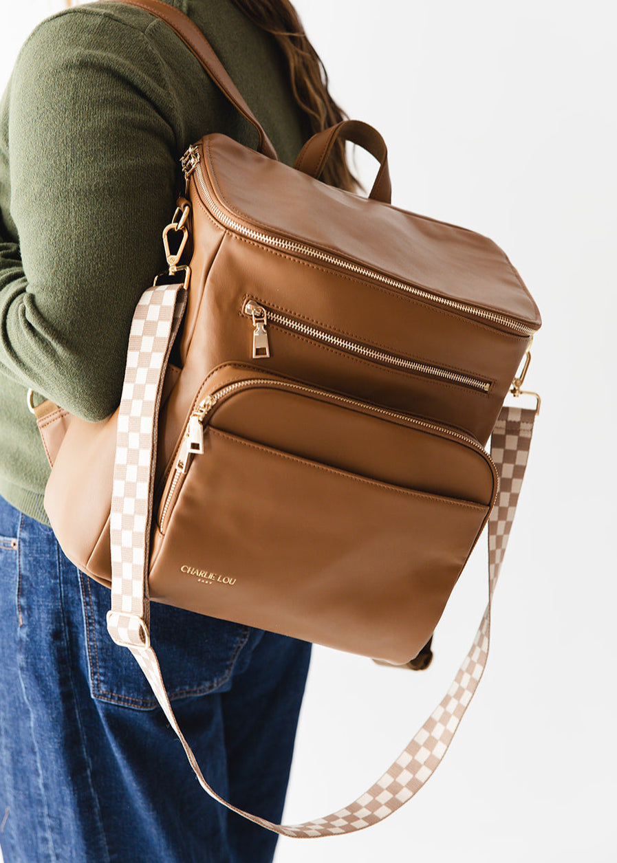 Brown faux leather large diaper bag with checkered cross body strap, insulated bottle pockets, changing mat, and stroller straps.