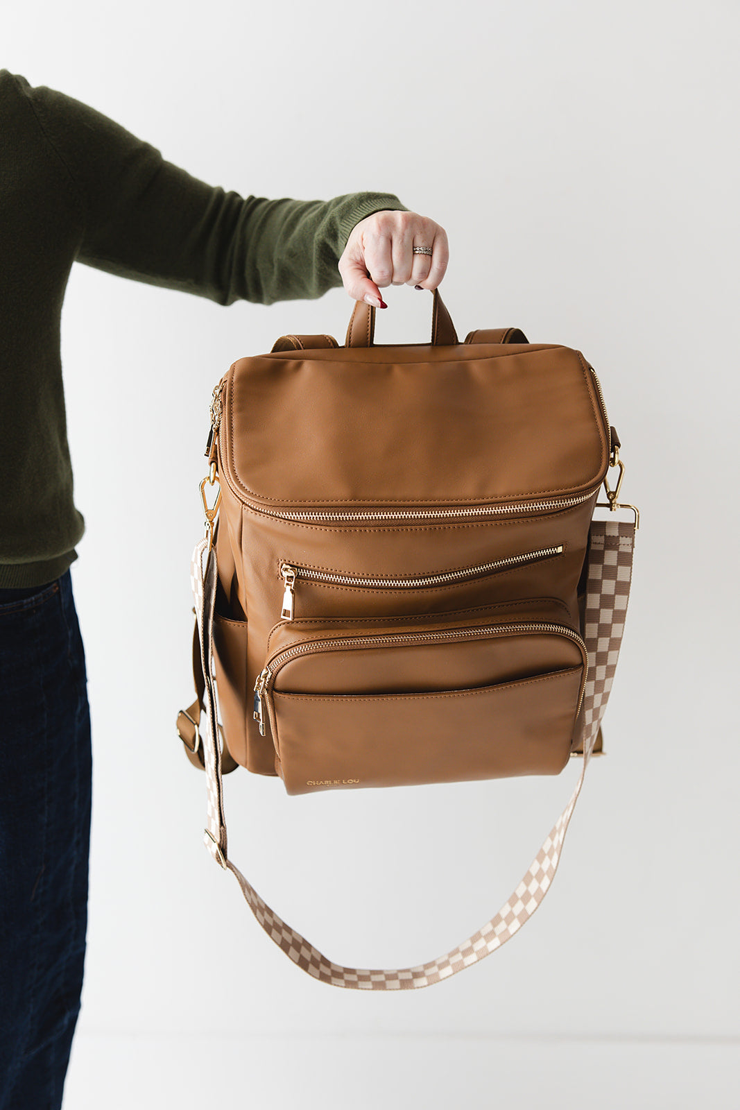 Brown faux leather large diaper bag with checkered cross body strap, insulated bottle pockets, changing mat, and stroller straps.