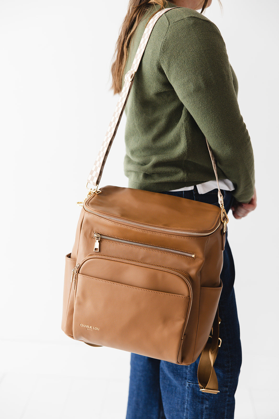 Brown faux leather large diaper bag with checkered cross body strap, insulated bottle pockets, changing mat, and stroller straps.