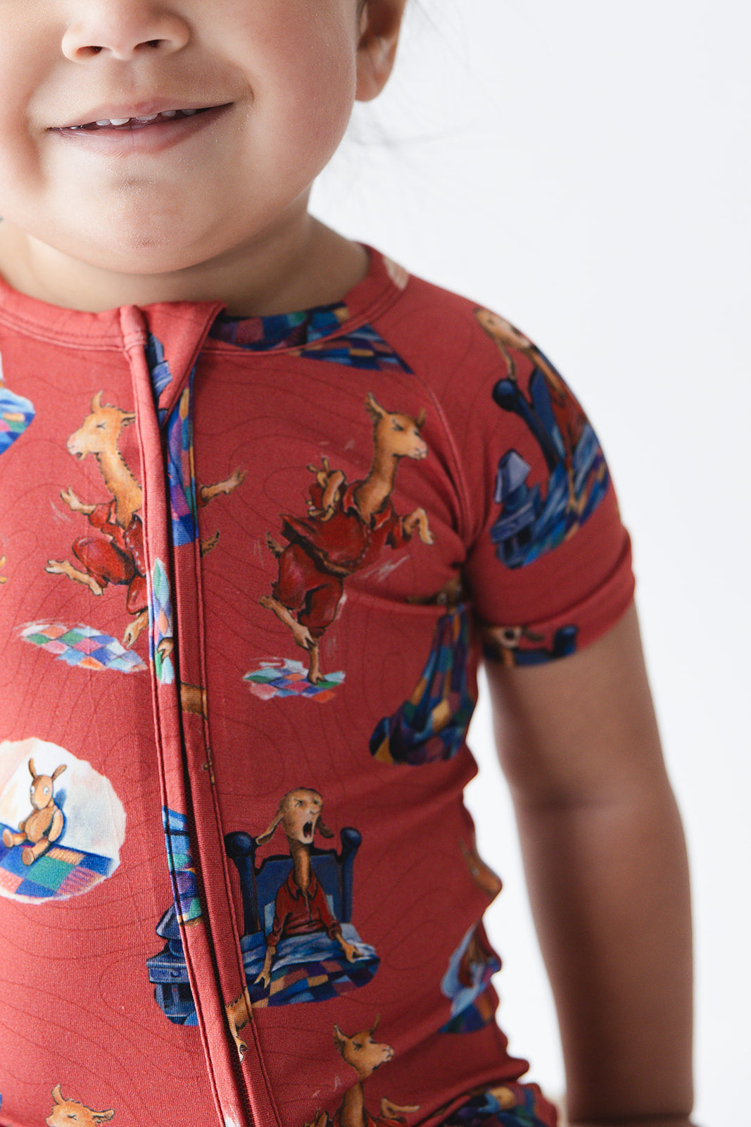 Bamboo double zipper shortie romper for babies and toddlers, both boys and girls. Print features a red background with Llama Llama Red Pajama.