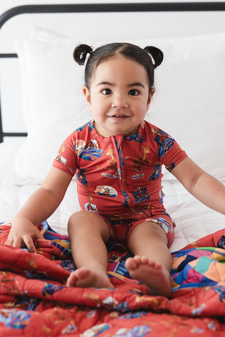 Bamboo double zipper shortie romper for babies and toddlers, both boys and girls. Print features a red background with Llama Llama Red Pajama.