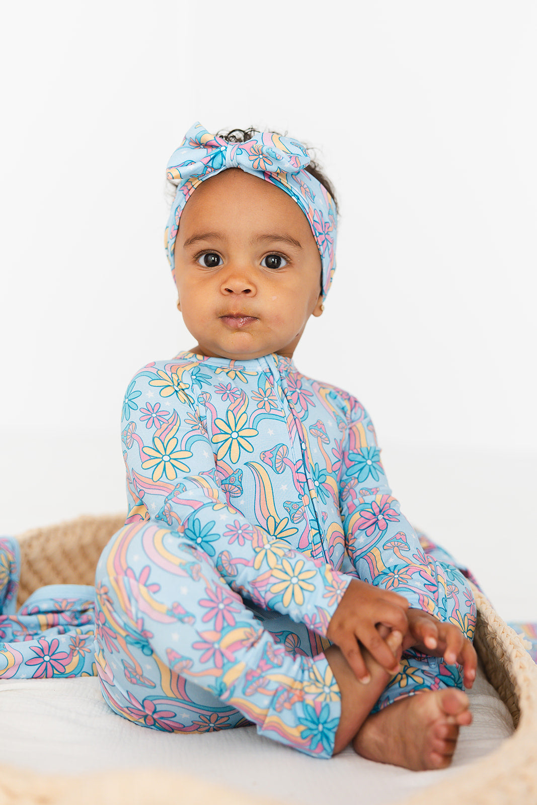 Convertible romper with hand and foot cuffs with bow made from super soft bamboo fabric. The print is a floral with mushrooms on it that looks very hippie, groovy, 70’s. Baby girl zippy with double zippers and fabric that is hypoallergenic, temperature regulating and has UV protection.