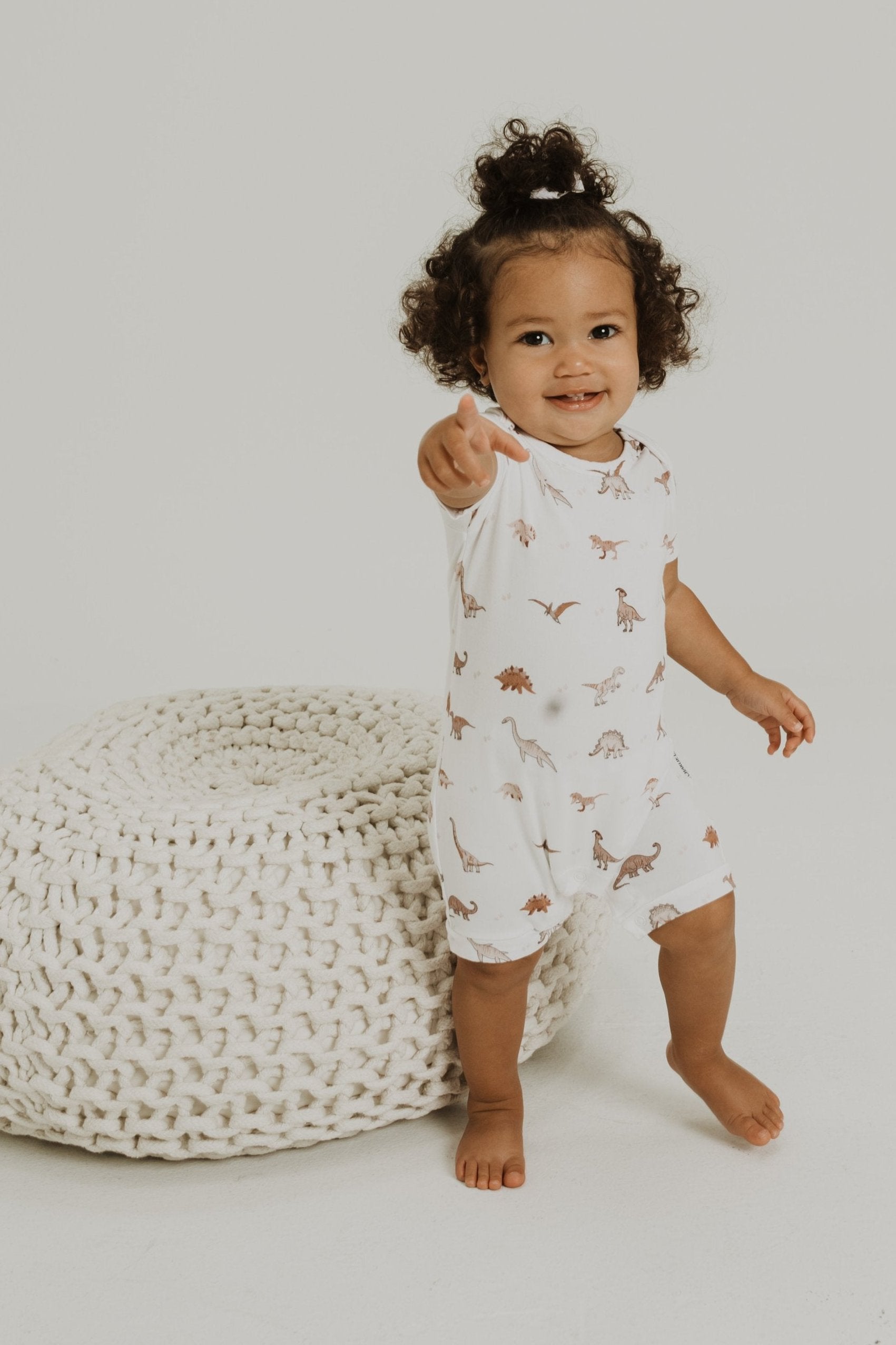Gender neutral short sleeve romper with crotch snaps made from bamboo with neutral dinosaur print for boys and girls.