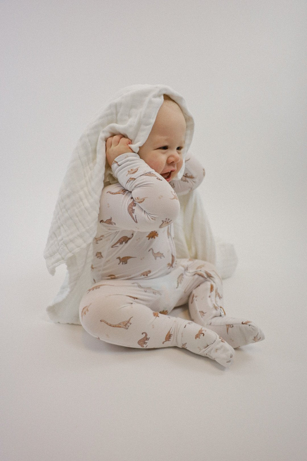 Double zipper baby romper with convertible hand & foot cuffs made from bamboo with neutral dinosaur print for boys or girls.