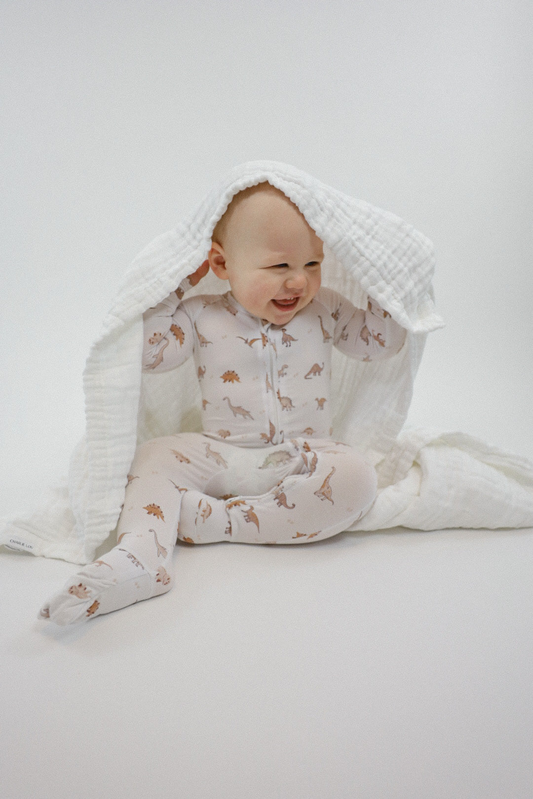 Double zipper baby romper with convertible hand & foot cuffs made from bamboo with neutral dinosaur print for boys or girls.