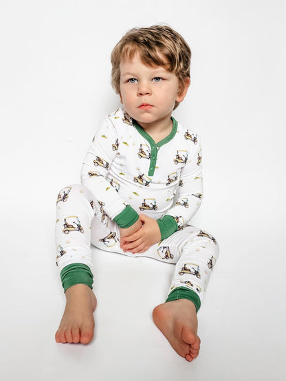 Gender neutral bamboo pajama set in golf sports print with green cuffs for toddler boys and girls.