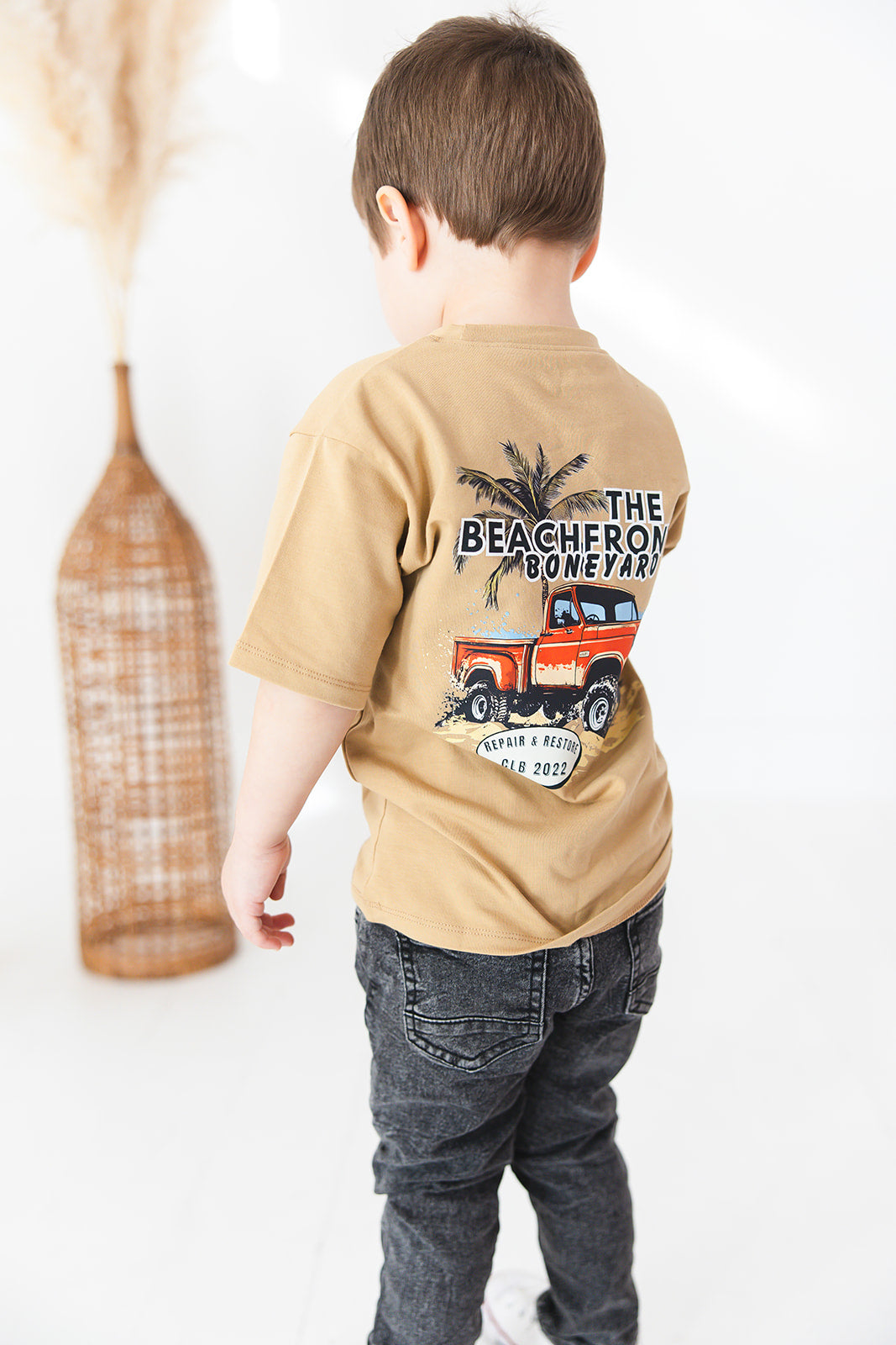 Skater style t-shirt for baby, toddler and little boys. Beige cotton shirt with a truck and palm tree graphic on the back. Soft, stretchy and thick fabric that is perfect for play with Charlie Lou Baby word logo on front.