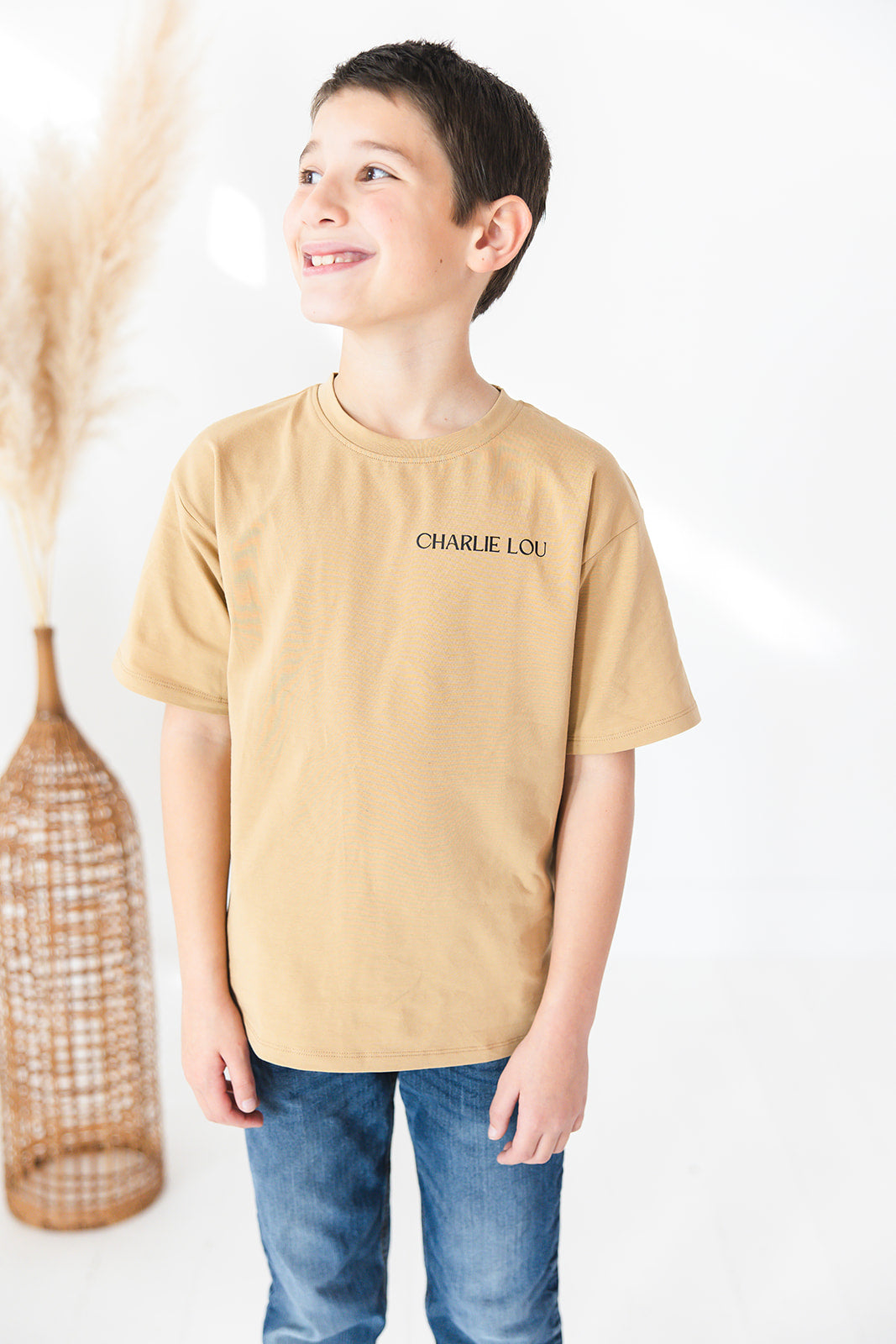 Skater style t-shirt for baby, toddler and little boys. Beige cotton shirt with a truck and palm tree graphic on the back. Soft, stretchy and thick fabric that is perfect for play with Charlie Lou Baby word logo on front.