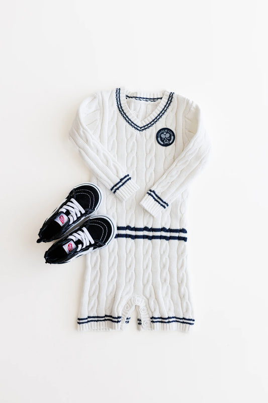 Gender neutral varsity sweater romper in cream and navy blue colors made from chain knit cotton for baby boys and baby girls as well as toddlers.