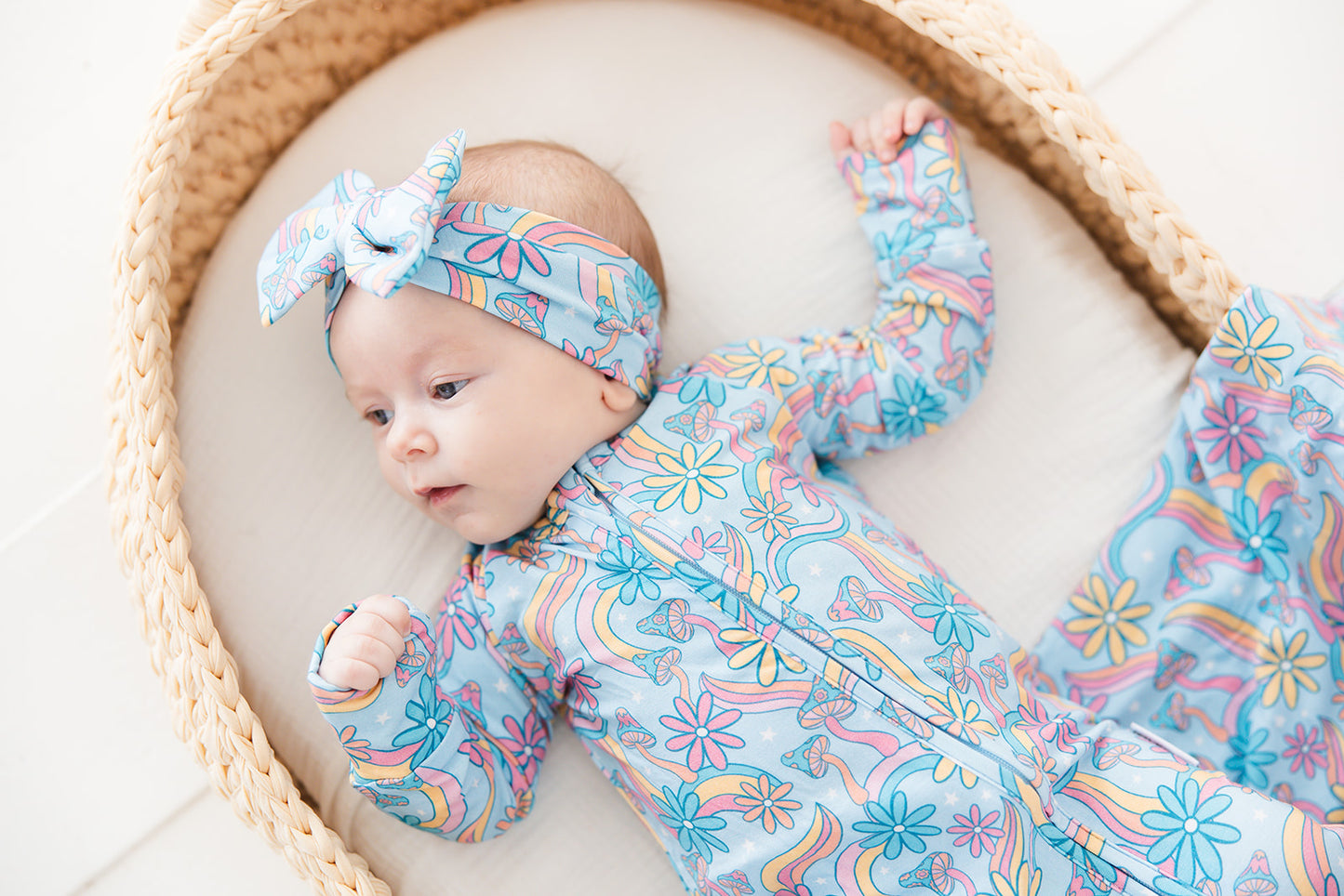 Convertible romper with hand and foot cuffs with bow made from super soft bamboo fabric. The print is a floral with mushrooms on it that looks very hippie, groovy, 70’s. Baby girl zippy with double zippers and fabric that is hypoallergenic, temperature regulating and has UV protection. 