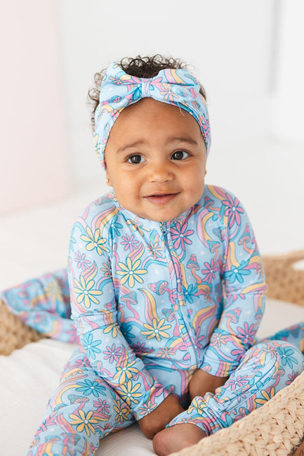 Convertible romper with hand and foot cuffs with bow made from super soft bamboo fabric. The print is a floral with mushrooms on it that looks very hippie, groovy, 70’s. Baby girl zippy with double zippers and fabric that is hypoallergenic, temperature regulating and has UV protection. 