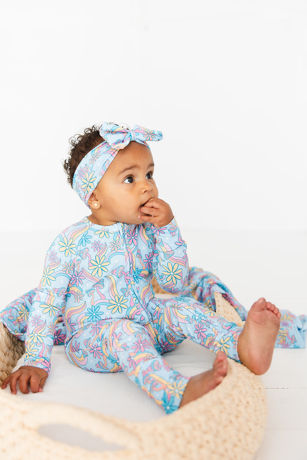 Convertible romper with hand and foot cuffs with bow made from super soft bamboo fabric. The print is a floral with mushrooms on it that looks very hippie, groovy, 70’s. Baby girl zippy with double zippers and fabric that is hypoallergenic, temperature regulating and has UV protection. 