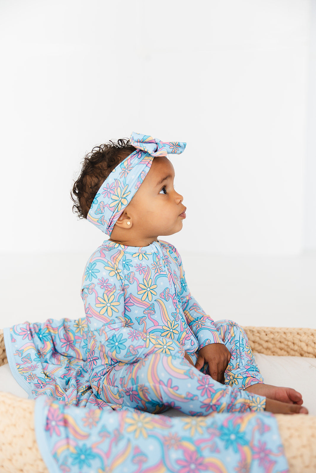 Convertible romper with hand and foot cuffs with bow made from super soft bamboo fabric. The print is a floral with mushrooms on it that looks very hippie, groovy, 70’s. Baby girl zippy with double zippers and fabric that is hypoallergenic, temperature regulating and has UV protection. 