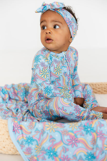 Convertible romper with hand and foot cuffs with bow made from super soft bamboo fabric. The print is a floral with mushrooms on it that looks very hippie, groovy, 70’s. Baby girl zippy with double zippers and fabric that is hypoallergenic, temperature regulating and has UV protection. 