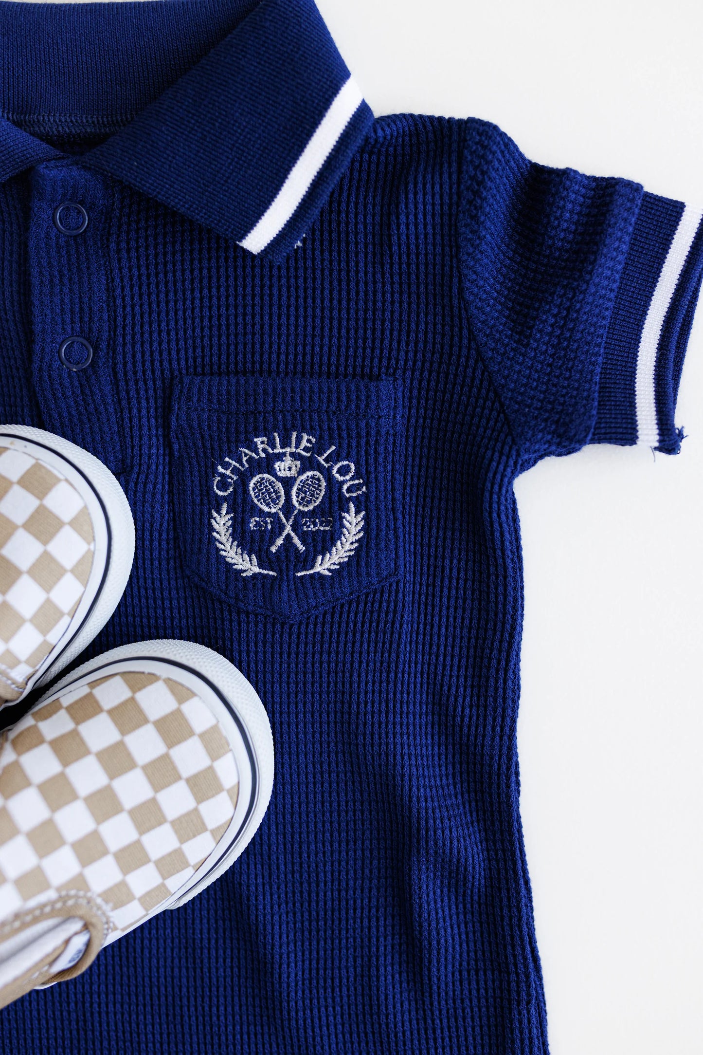 Preppy boys short sleeve polo romper with crotch snaps made from blue waffle bamboo & embroidered with Charlie Lou Baby Club.