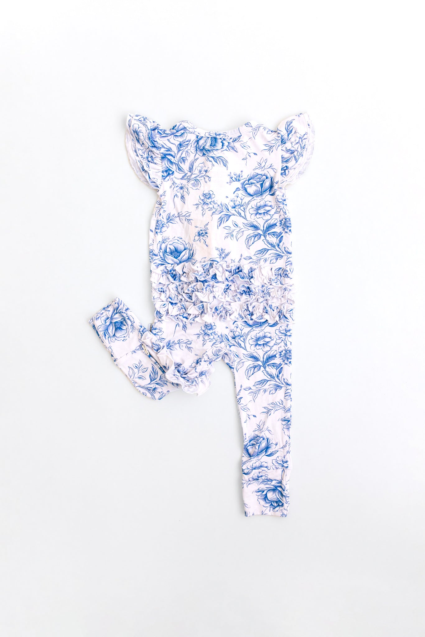 Baby girl wearing blue floral toile bamboo pajamas with ruffles and bamboo bow.