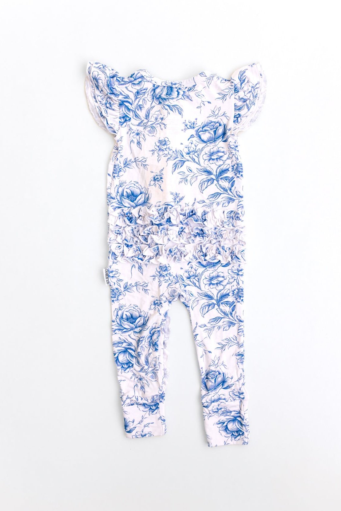 Baby girl wearing blue floral toile bamboo pajamas with ruffles and bamboo bow.