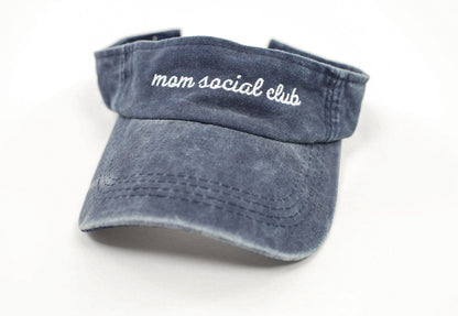 Washed and vintage style visor which is blue with words mom social club on it.