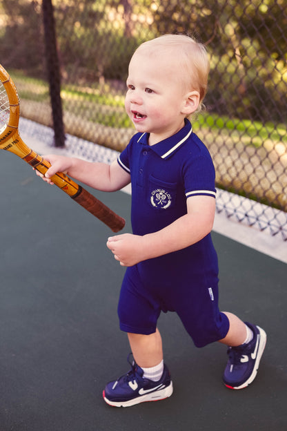 Preppy boys short sleeve polo romper with crotch snaps made from blue waffle bamboo & embroidered with Charlie Lou Baby Club.