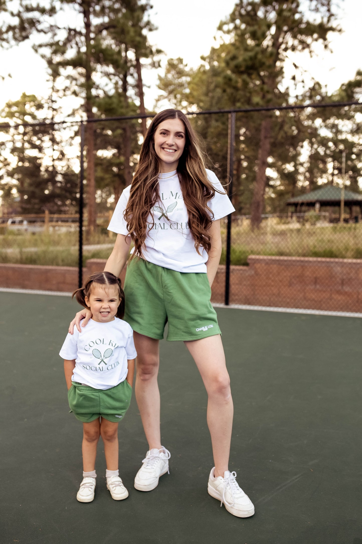 White women's t-shirt with green graphic that says Cool Mom Social Club in crew neck style.