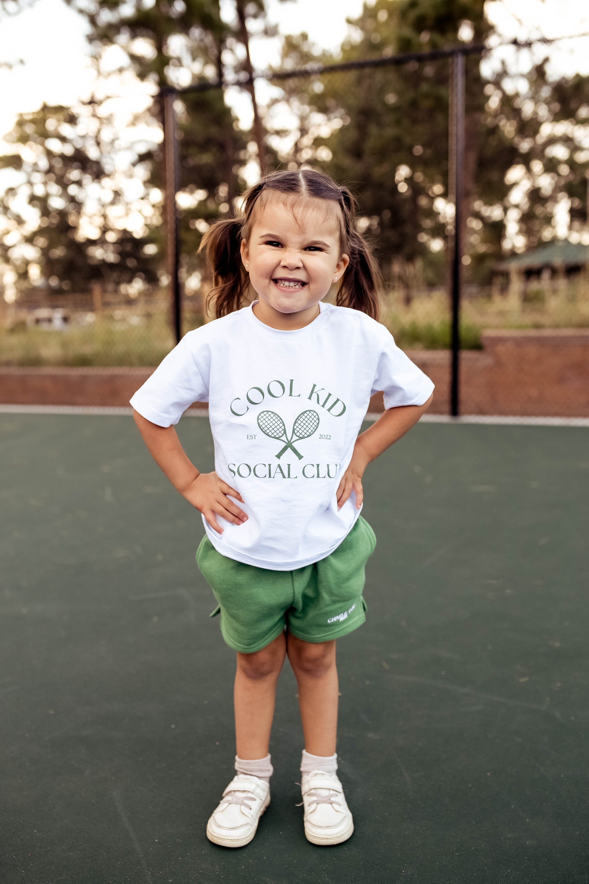 Cool Kid Club white T-Shirt with green graphic which is gender neutral for boys and girls with shoulder snaps.