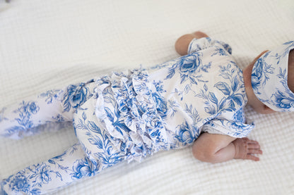 Baby girl wearing blue floral toile bamboo pajamas with ruffles and bamboo bow.