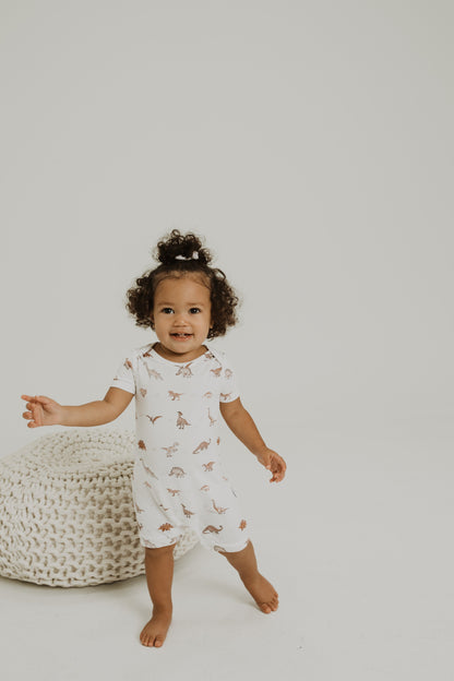 Gender neutral short sleeve romper with crotch snaps made from bamboo with neutral dinosaur print for boys and girls.