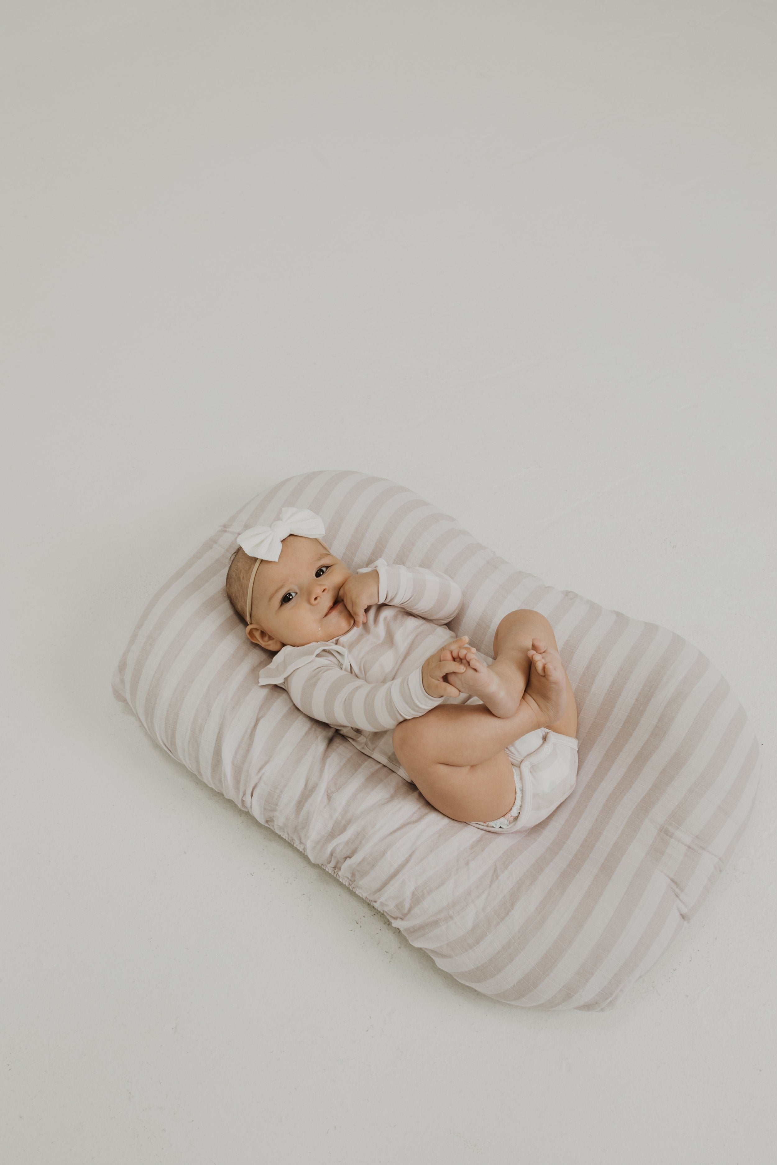 Ruffle bamboo bodysuit with crotch snaps and hand cuffs in neutral striped print.