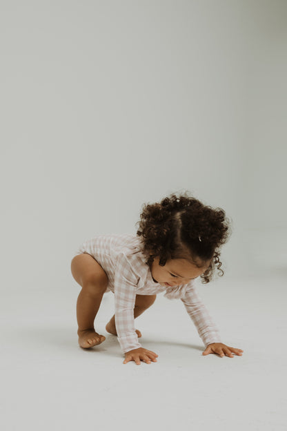 Ruffle bamboo bodysuit with crotch snaps and hand cuffs in peach and pink gingham.