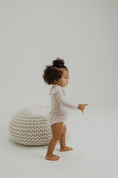 Ruffle bamboo bodysuit with crotch snaps and hand cuffs in peach and pink gingham.